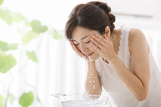 水で顔を洗う女性